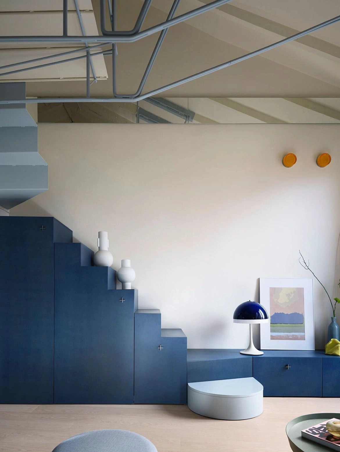 Dans cet agencement sur mesure, le linéaire de rangements bas se prolonge en formant les marches de cet escalier à double quarts tournants.