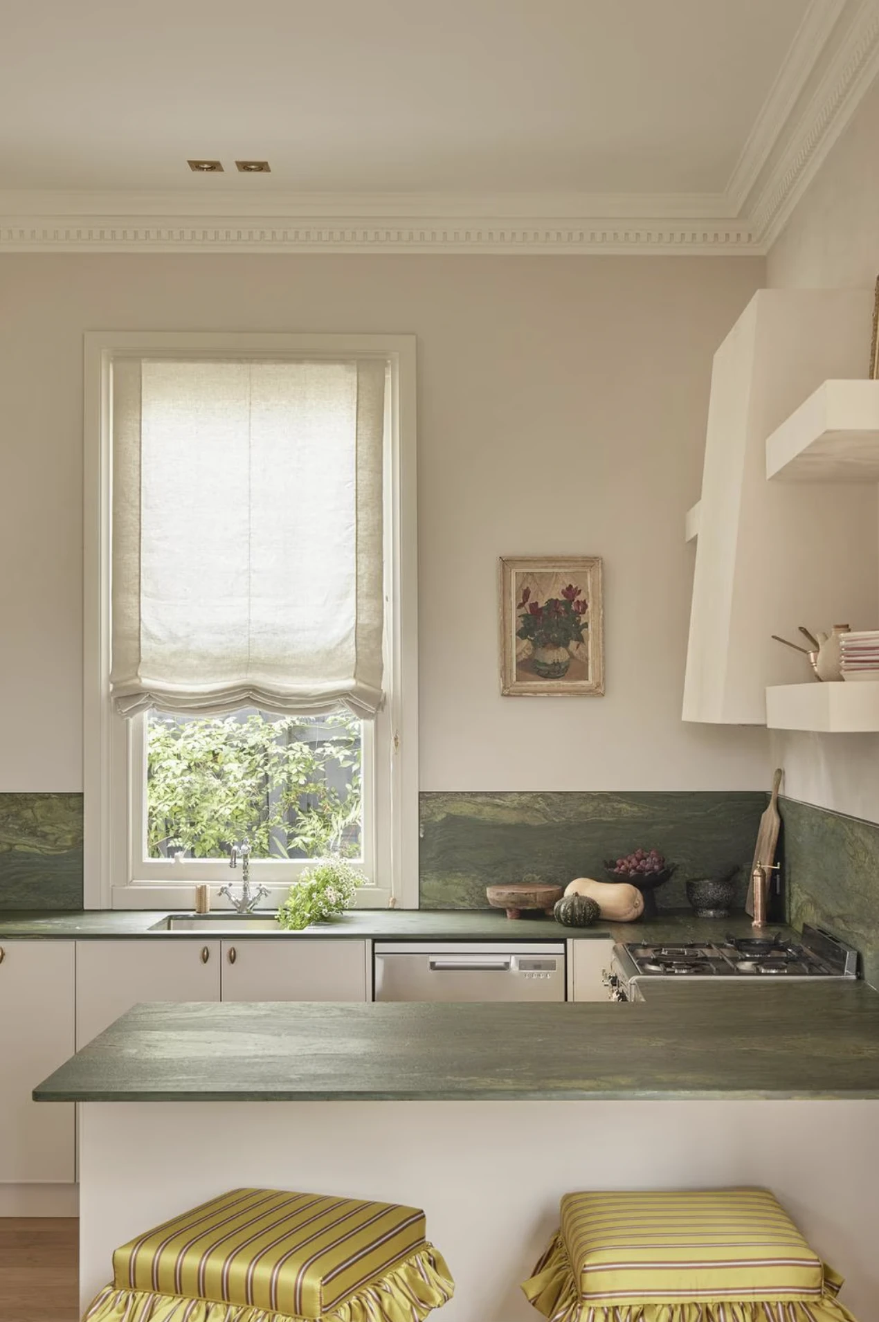 Cuisine contemporaine aux lignes épurées avec un tableau ancien chiné au-dessus du plan de travail et des assises habillées de tissus vintage.