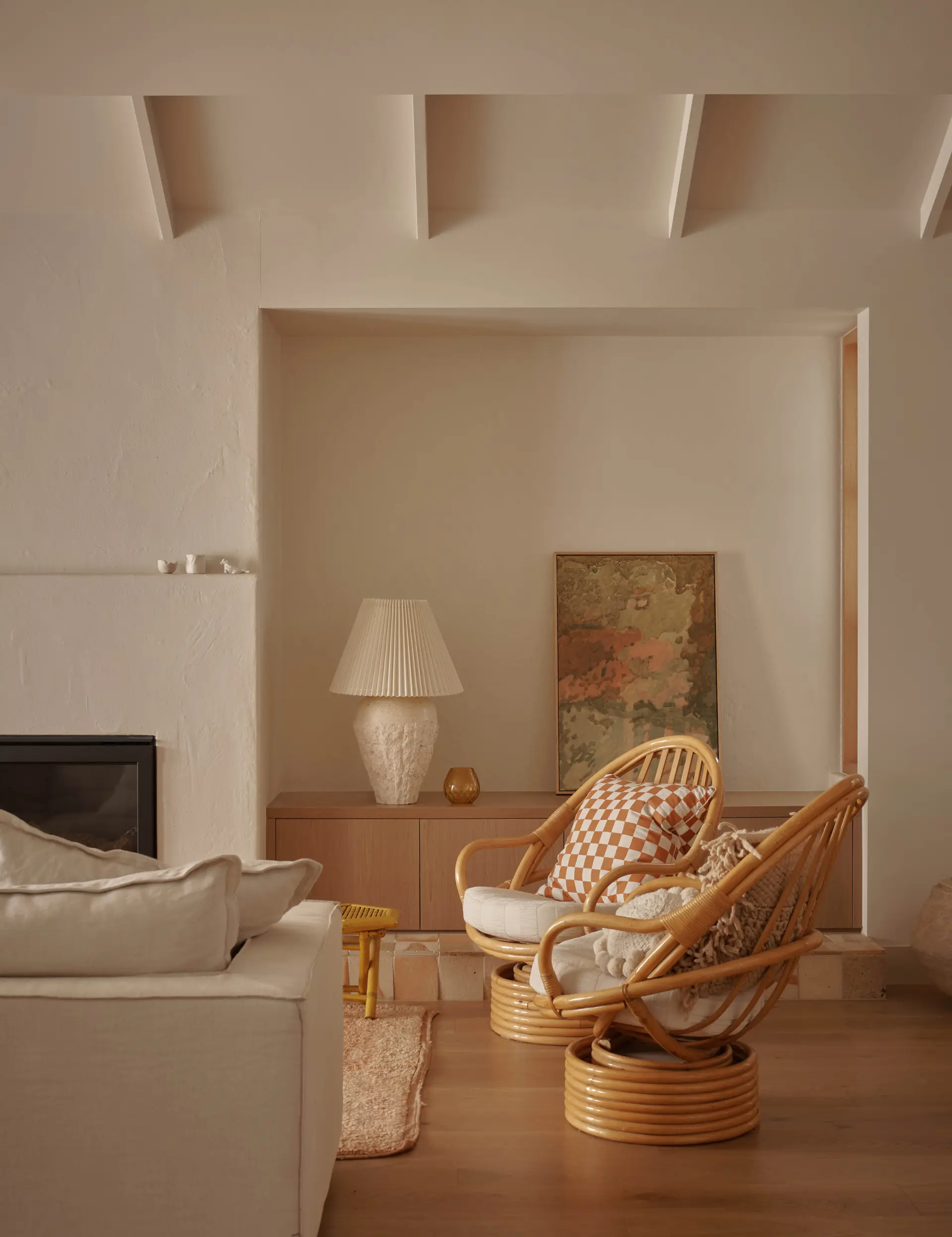 Salon aux lignes épurées avec deux fauteuils en rotin des années 50 et un mobilier contemporain discret.