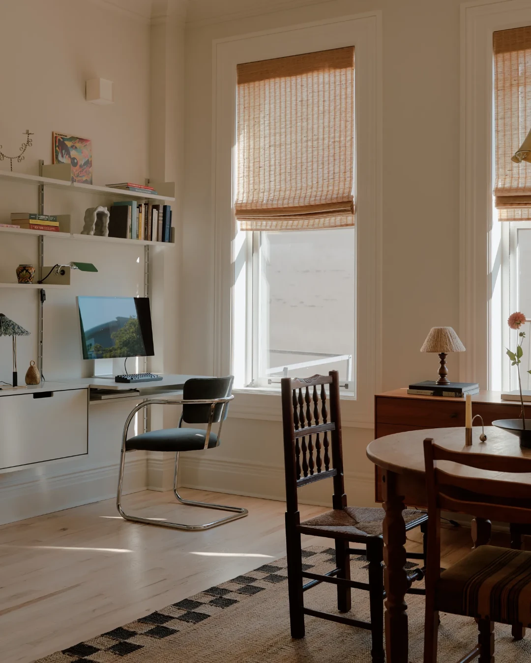 Salle à manger faisant office de bureau avec un mobilier vintage mêlant différentes époques, associé à des murs clairs et un aménagement sobre.