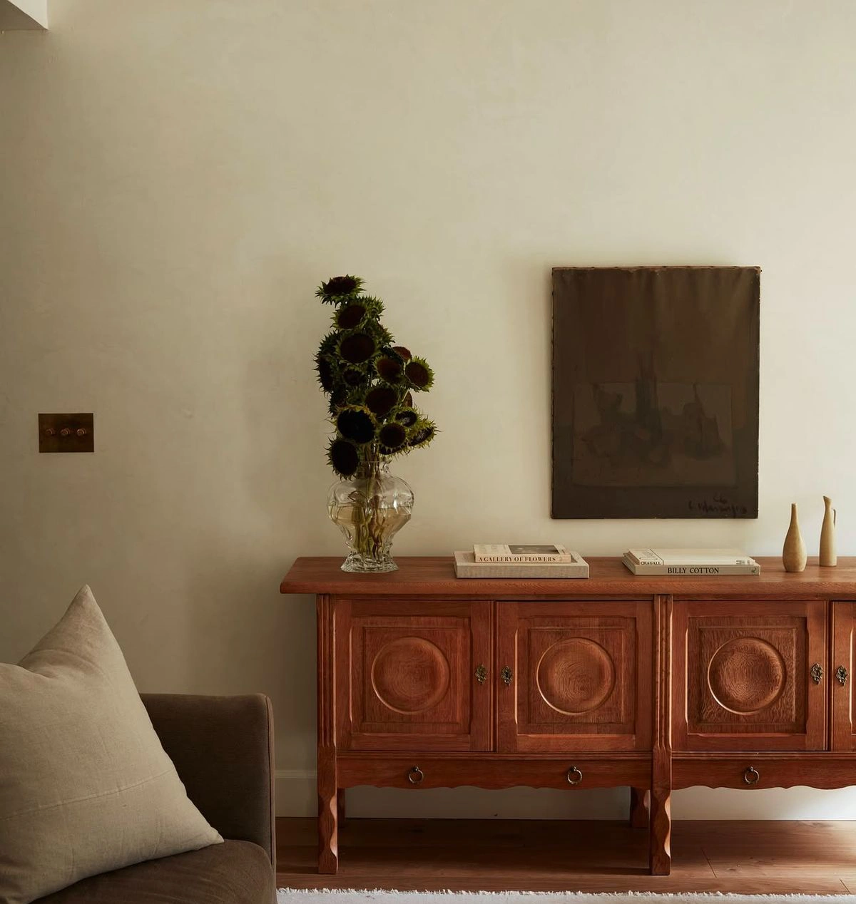 Enfilade ancienne en bois foncé associée à des objets décoratifs minimalistes et une œuvre murale contemporaine, créant une ambiance singulière et intemporelle.