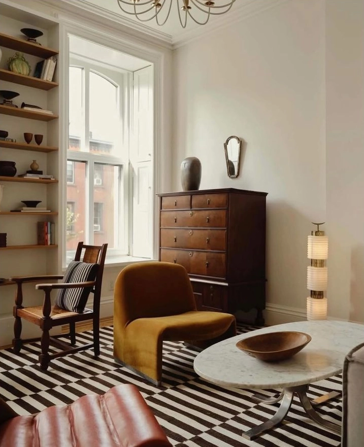 Salon lumineux mêlant commode ancienne en bois foncé, fauteuil contemporain et tapis graphique, illustration d’une décoration moderne avec meubles anciens.