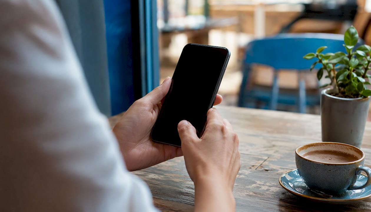 Hand pressing phone publish button in home studio