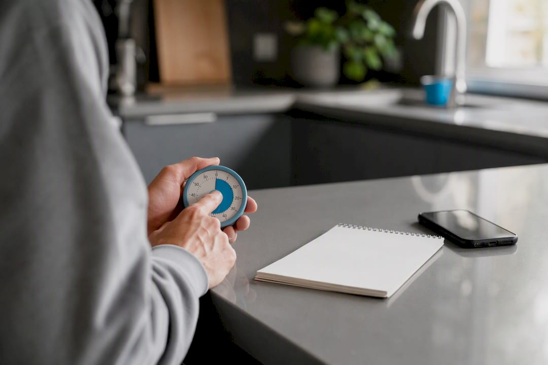 Hands adjusting timer on desk with digital notepad