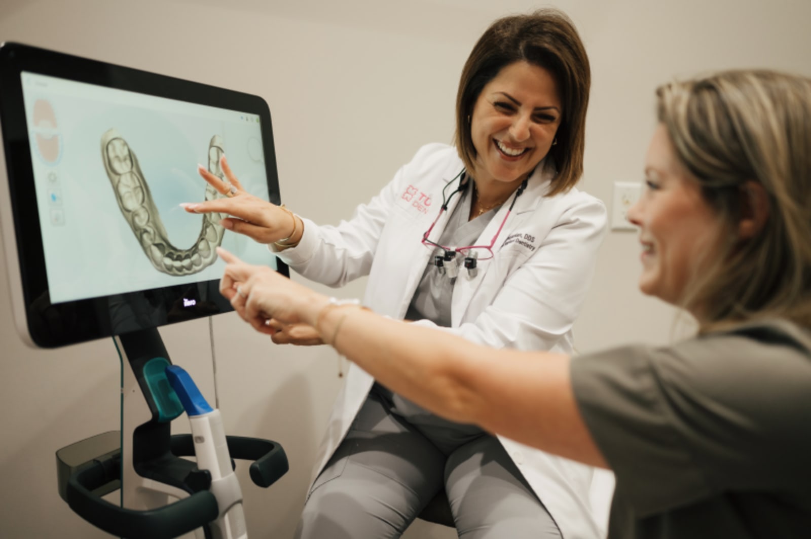 Dentist pointing to digital teeth scan on monitor while patient watches consultation