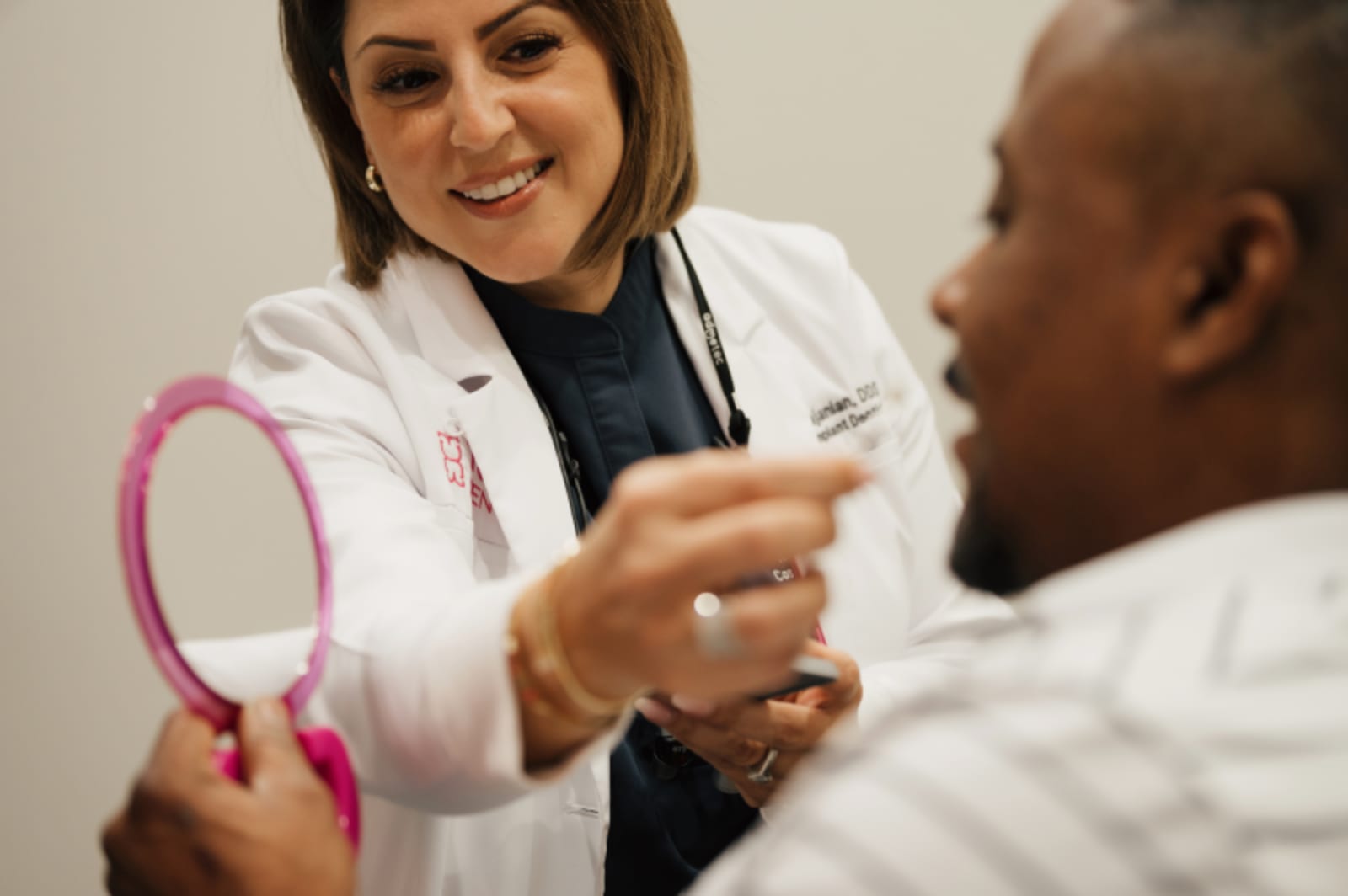 Dentist explaining teeth model to smiling patient in clinical setting