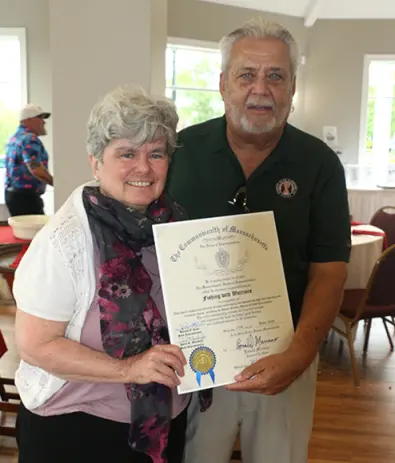 Older couple smiling while holding an official certificate together