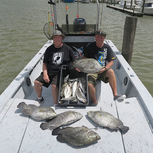 Two anglers in boat with large catch of fish at marina