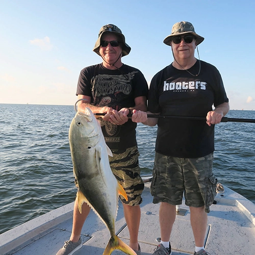 Two men on a boat holding a large fish on a sunny day