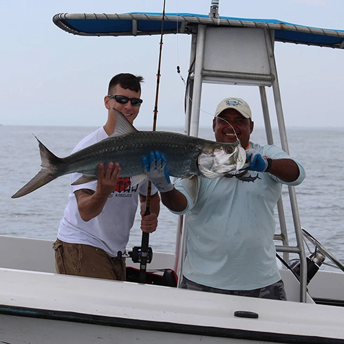 Two fishermen showing off large catch on a boat offshore