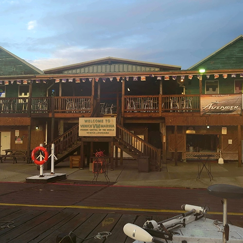 Wooden two-story building with "Welcome to VW Marina" sign and vintage props