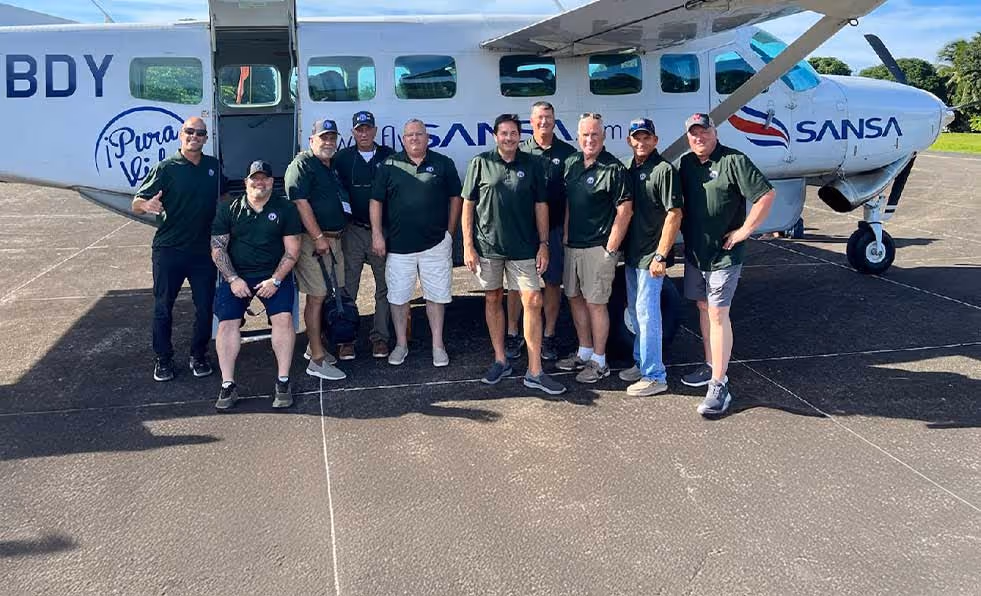 Group of employees posing in front of a Sansa Airlines small aircraft