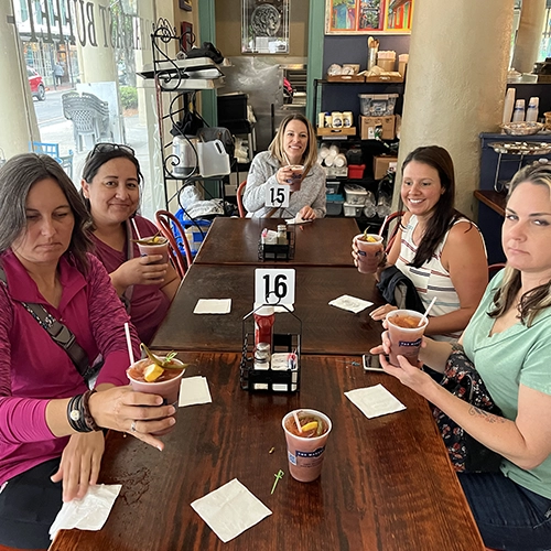 Five women gathered at a table enjoying drinks in a cozy cafe