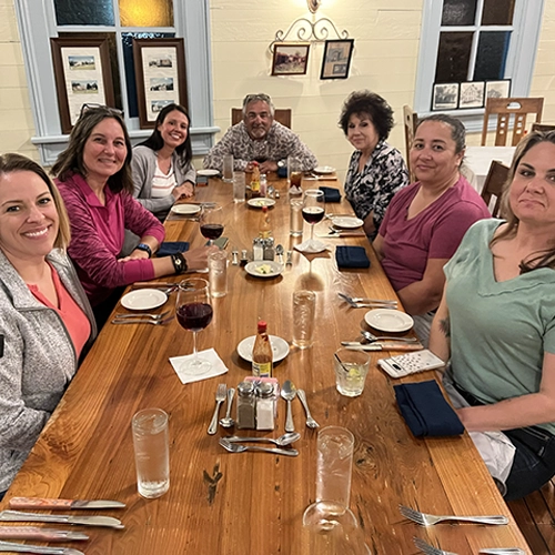 Group of friends enjoying dinner together around a wooden table