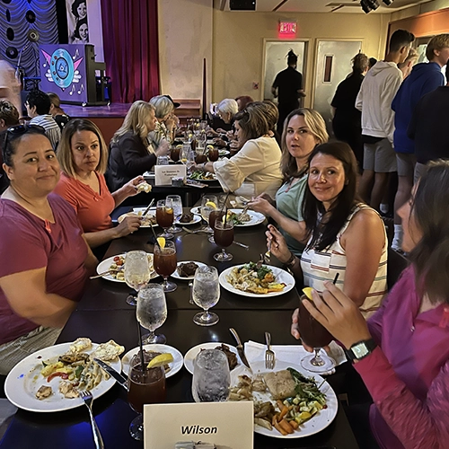 Group of people sitting at a long table enjoying a meal together