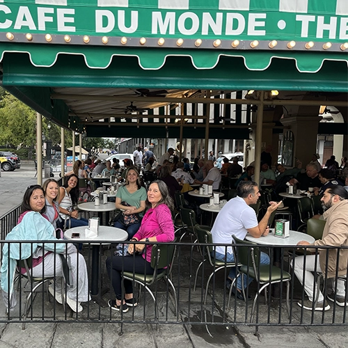Busy outdoor seating at Cafe Du Monde with people enjoying coffee and atmosphere