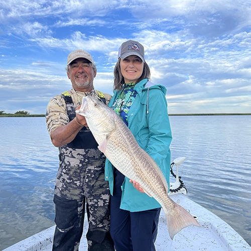 Two anglers proudly display large fish on boat with cloudy sky background