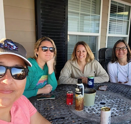 Four women enjoying conversation and drinks on a porch patio