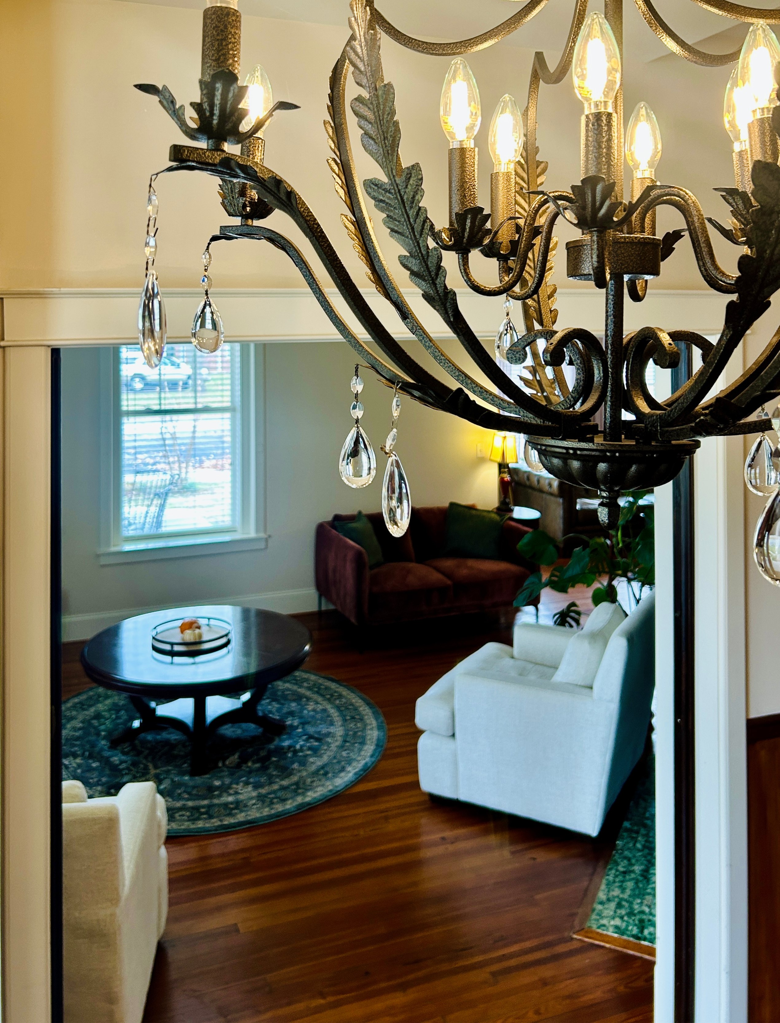 Chandelier in the foyer at The Grand Lux Inn with a view into the living room beyond