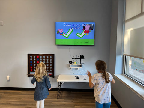 two female kids playing peppa pig jump and giggle at the clinic