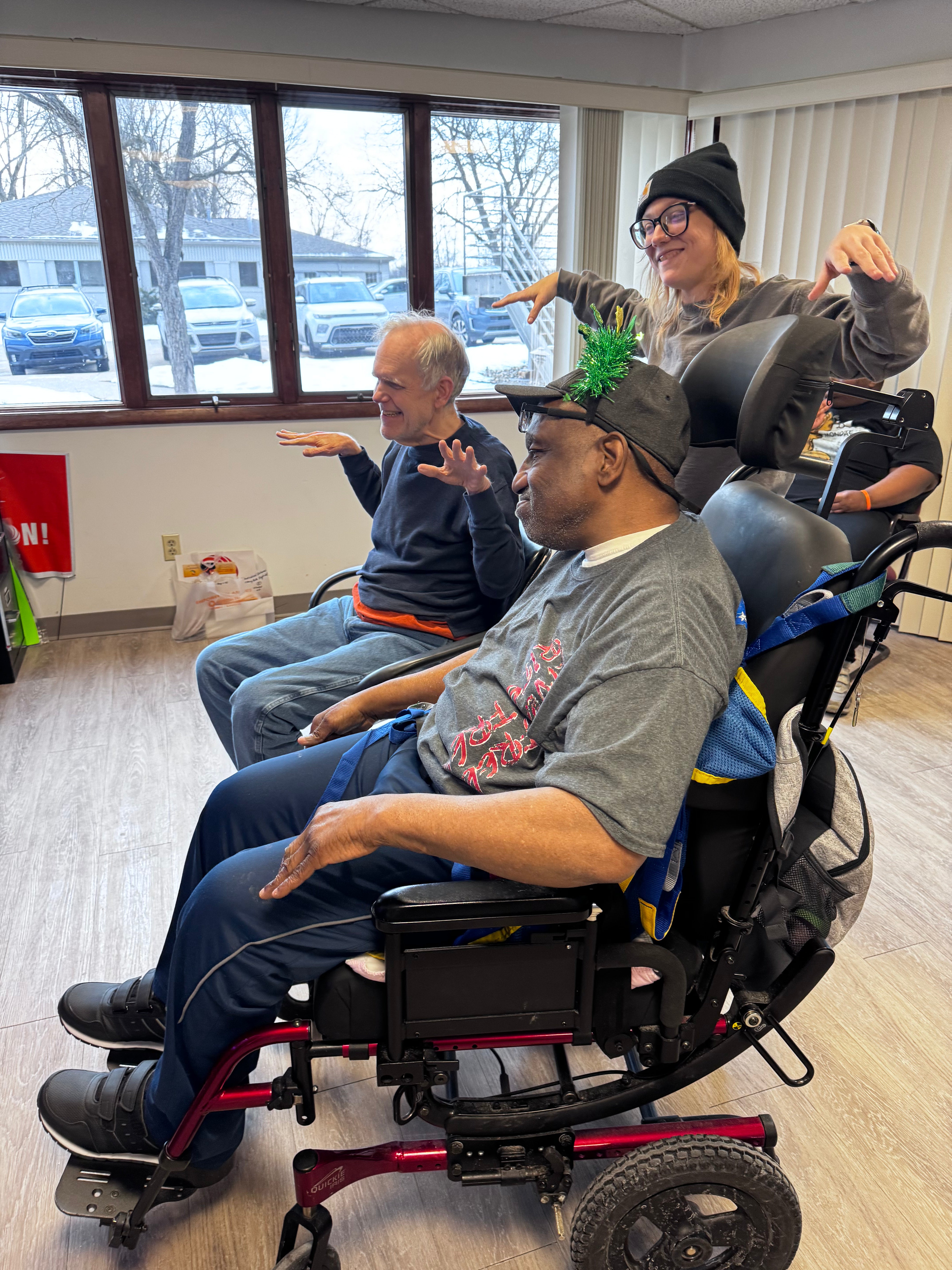 Image of 2 older men seated and playing with the help of an Individual Outcomes employee