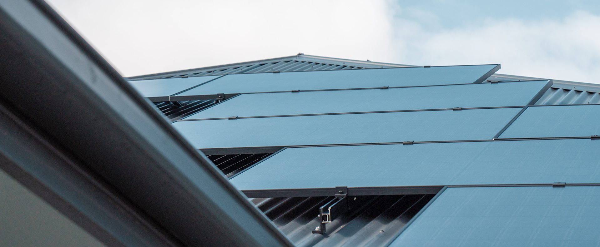 Close-up of solar panels installed on a rooftop against a cloudy sky.