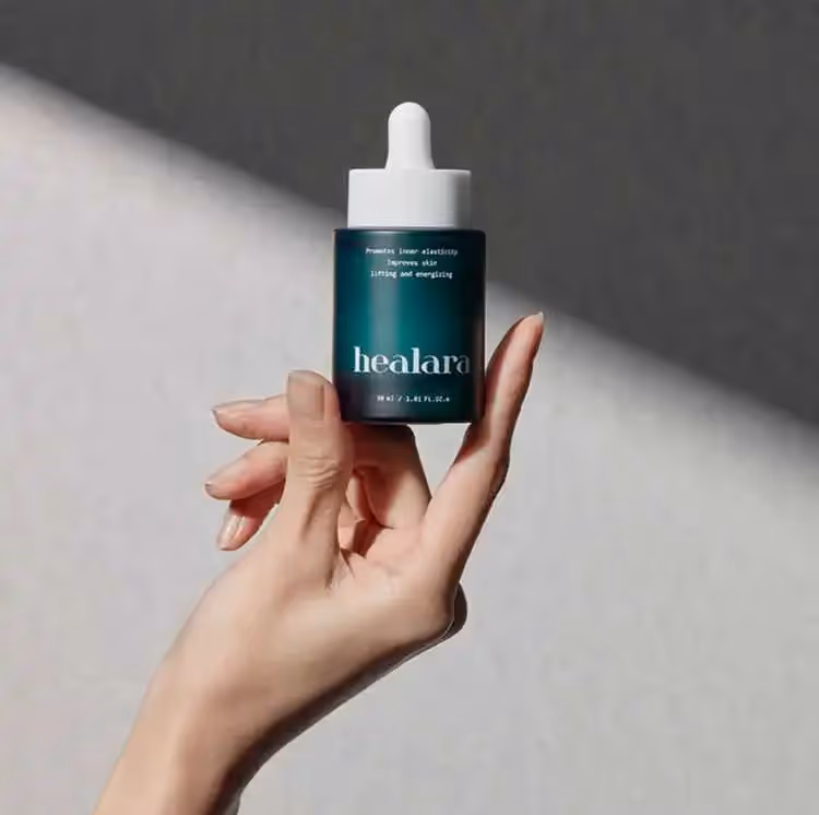 A woman's hand holding up an ampoule of healara product