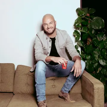 stan van samang boeken die een witte jas aanheeft en voor een oude microfoon staat