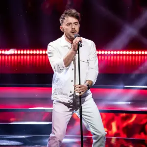 dean boeken in wit kostuum zingend op podium