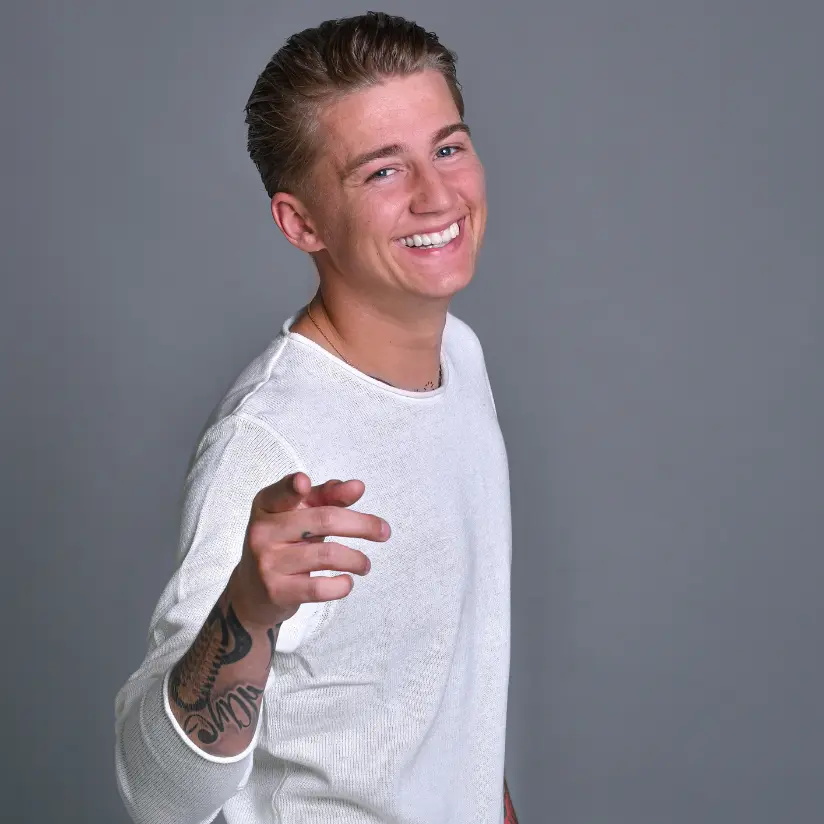 mart hoogkamer boeken met witte trui en grijze achtergrond en wijst naar camera