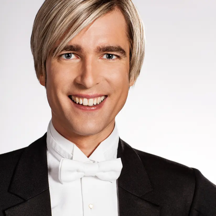 showbizz bart boeken met kostuum aan voor witte achtergrond en is aan het lachen