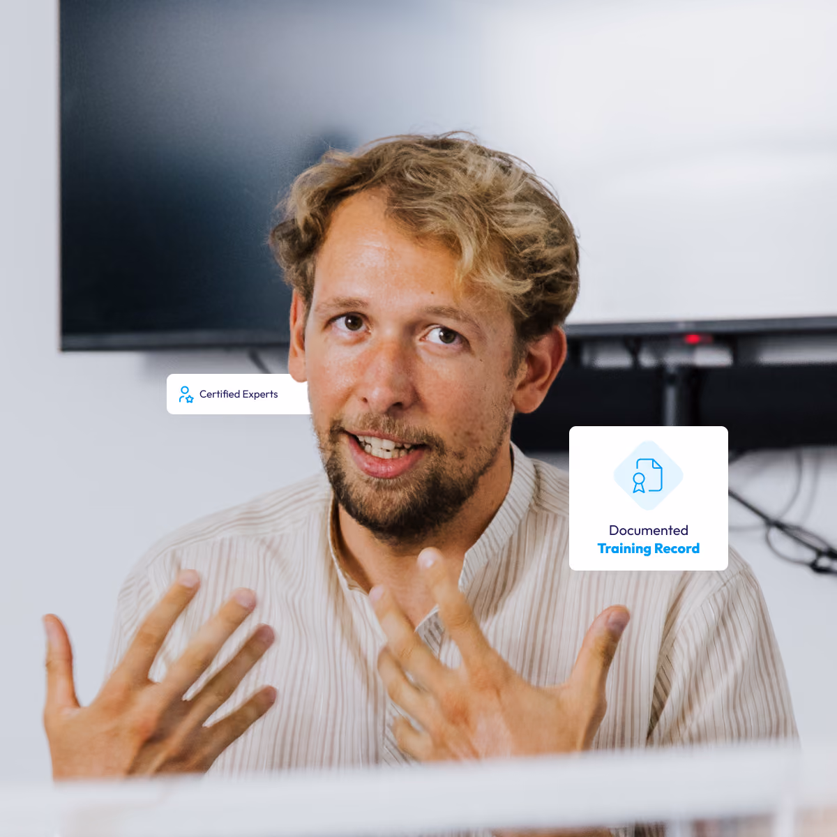 Man explains something with hands, a screen in the background, with texts about experts and training certificates.