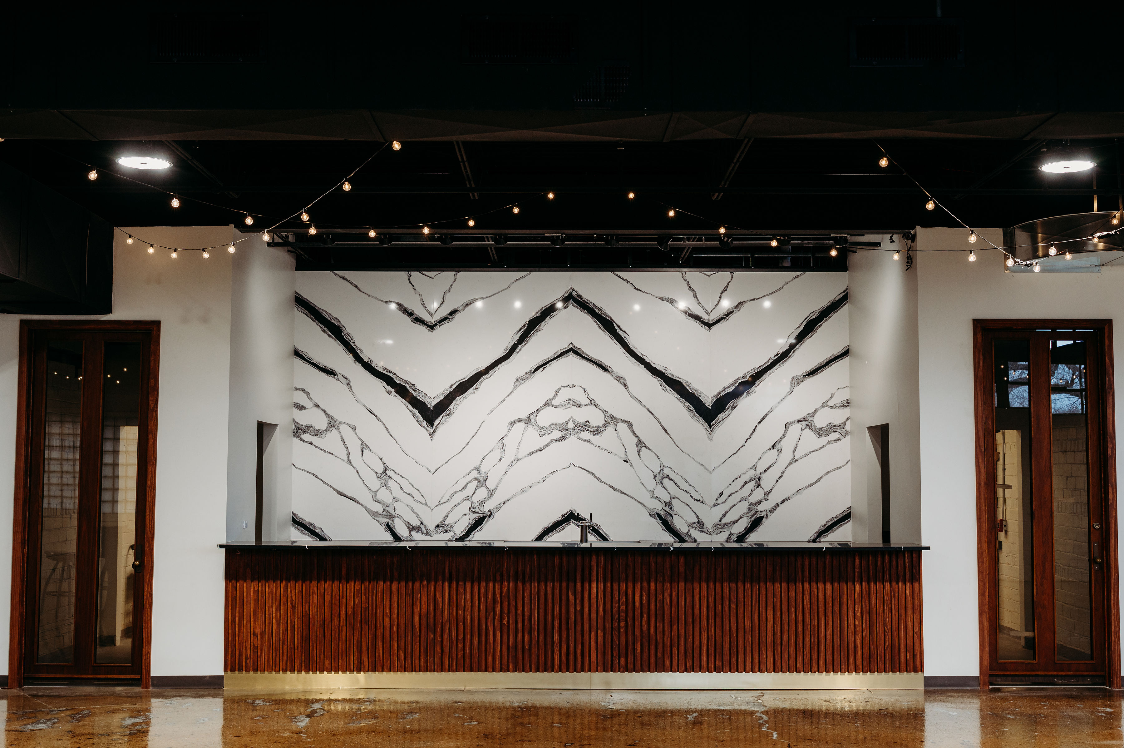 A picture of our stunning elevated bar. Black and white marble back splash with dark transposed counter tops. Dark wood underneath the bar top. 