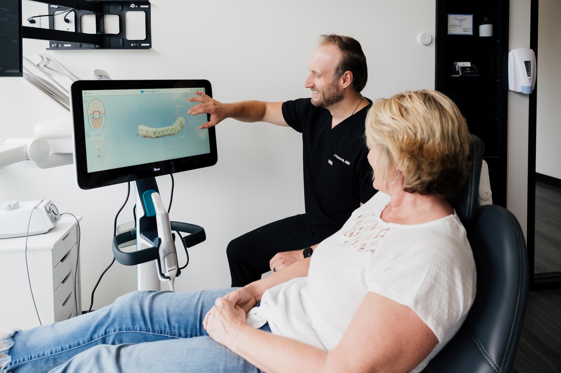 A close-up view of a clear dental aligner next to a beige dental model labeled "Candid," placed on a light-colored surface. The setup highlights orthodontic treatment tools.