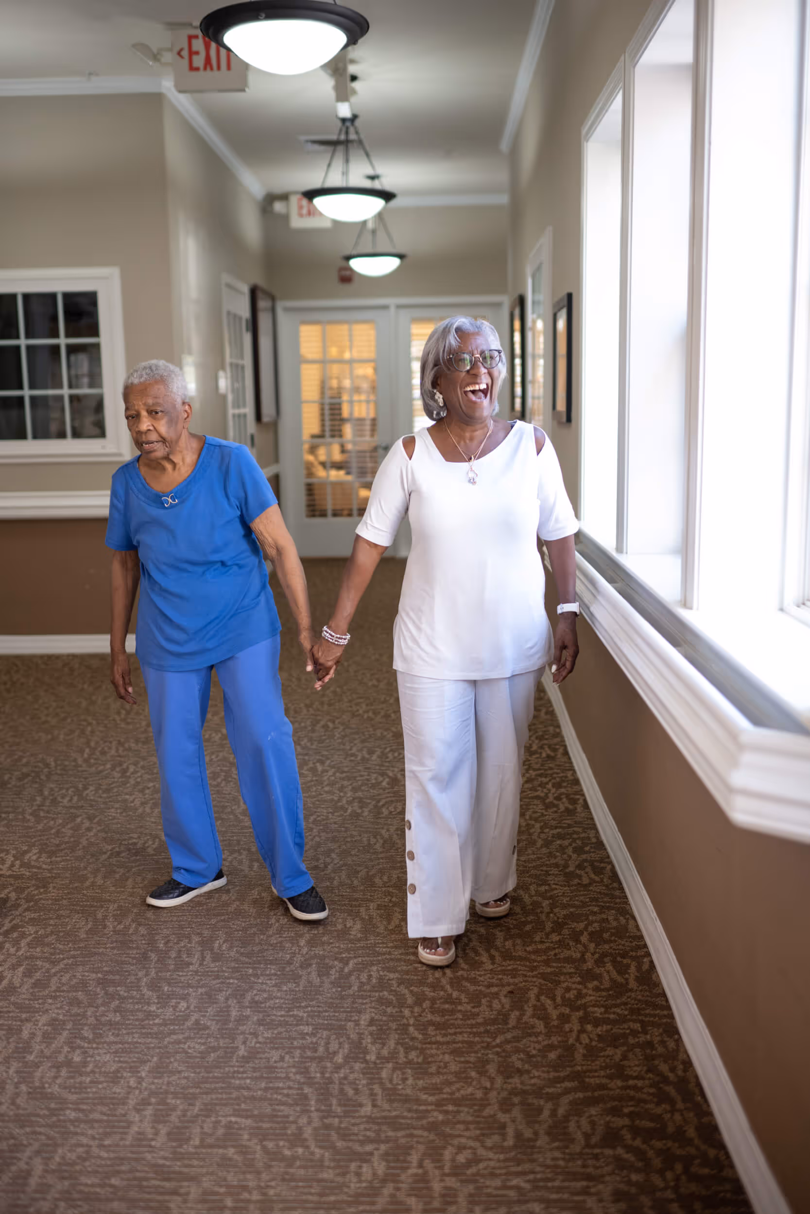 Two senior women walk hand in hand, smiling