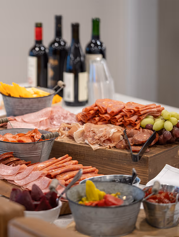 Gourmet charcuterie spread with assorted meats, cheeses, and wine at a senior living community event.