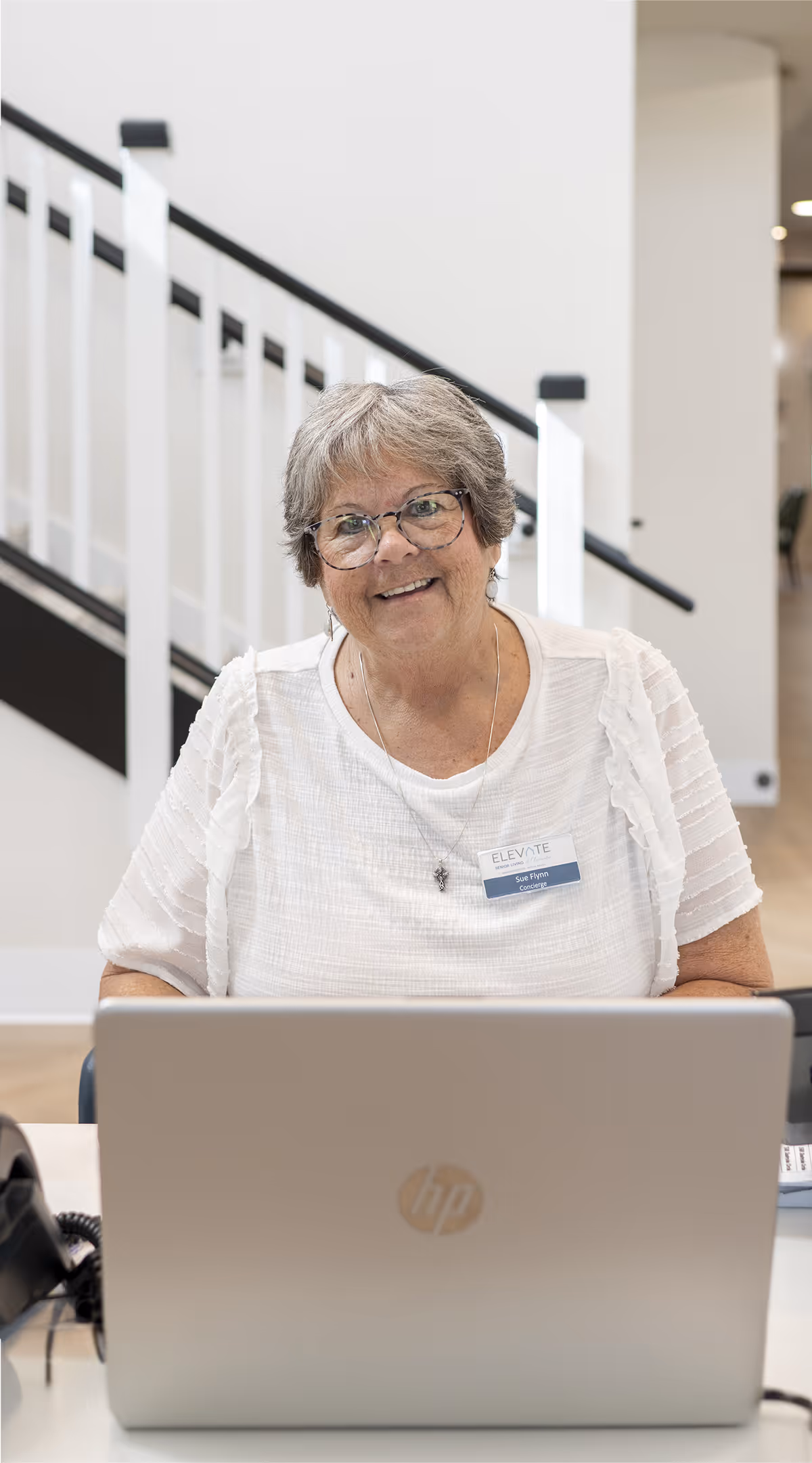 Friendly senior living concierge smiling at the front desk, ready to assist residents.