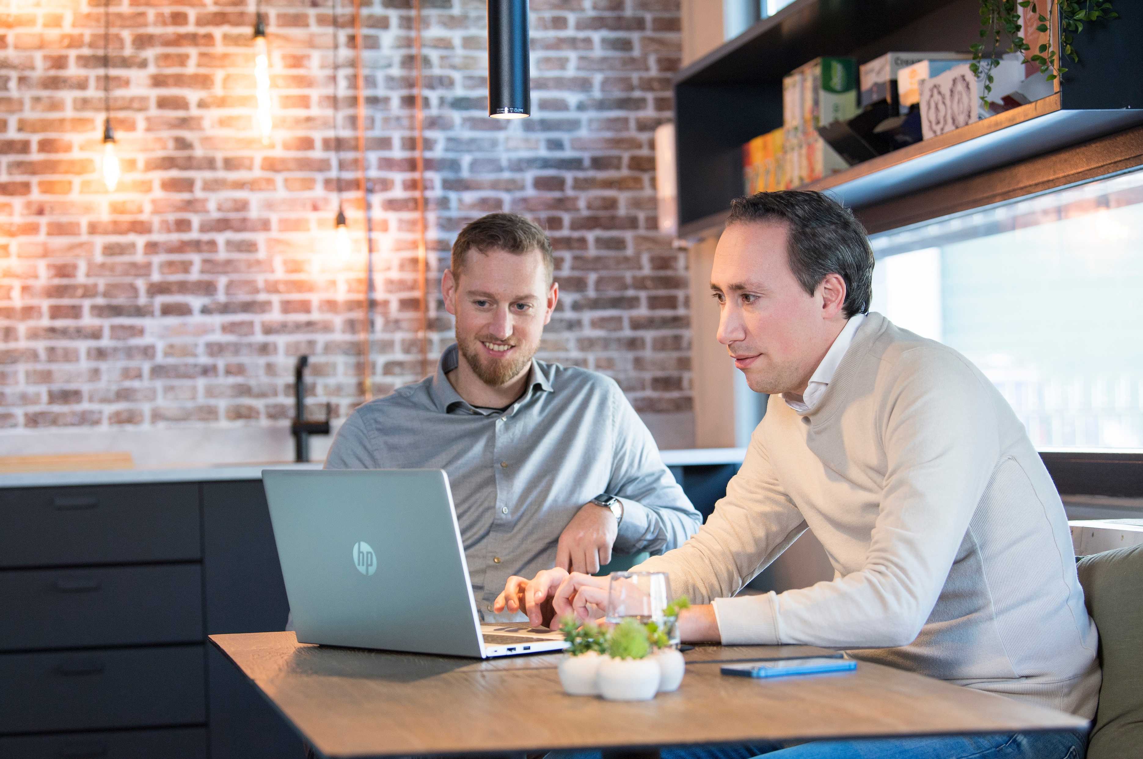 Twee collega’s van R-ffect werken samen achter een laptop