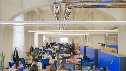 Large open space of Nana Bianca's coworking in Florence, with shared desks, ergonomic seats and a bright environment ideal for teamwork and productivity.