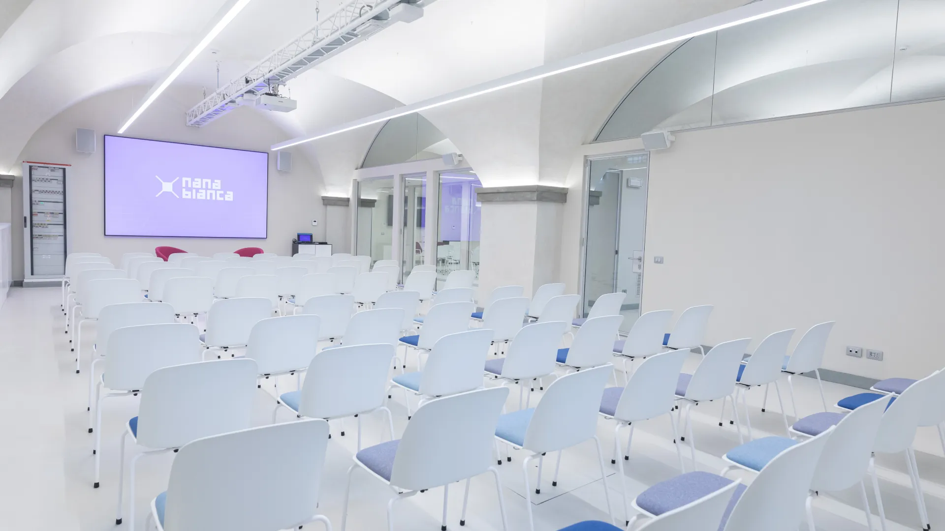 Conference room in Florence with “Nana Bianca” screen, comfortable audience; audio-video and internal direction for corporate events and workshops.