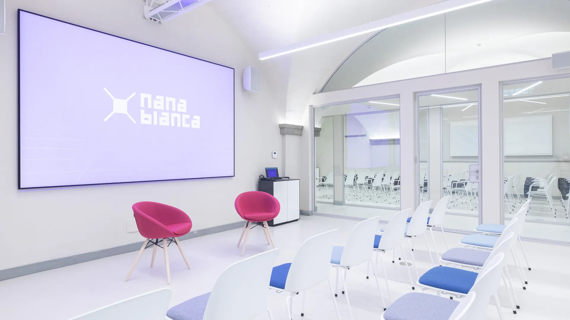 Minimal meeting room in Nana Bianca Florence; transparent seats, glazed wall, configurable spaces with multimedia support for team meetings.