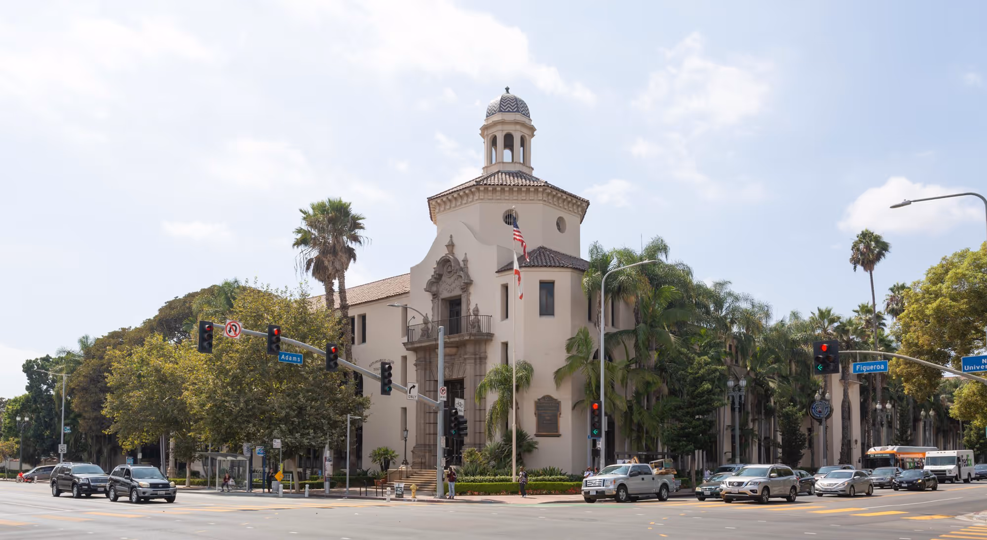 Image of the University of Southern California campus with iconic red-brick buildings, palm trees, and students walking across the central courtyard.