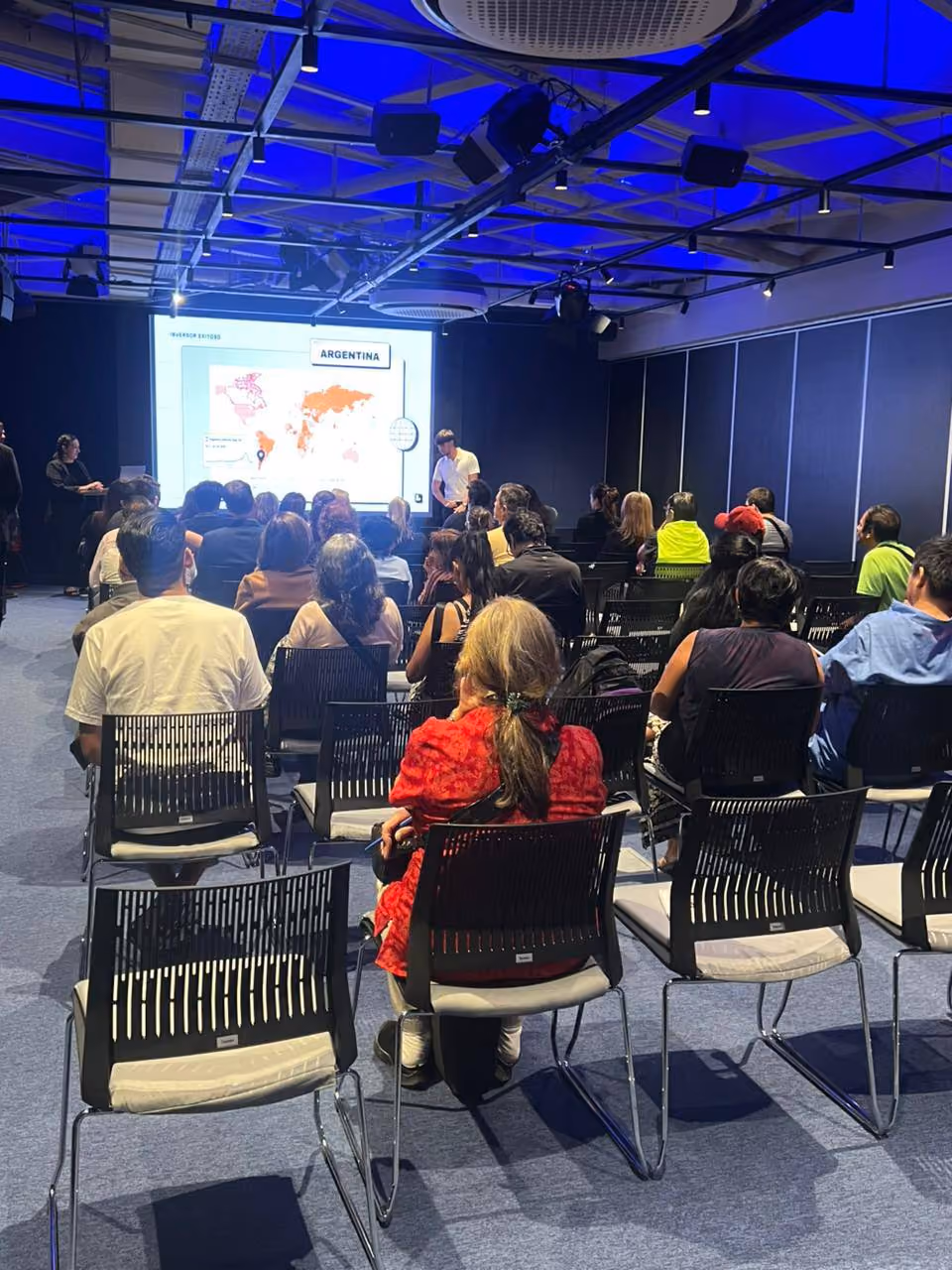 Grupo de personas sentadas mirando una presentación en proyector que muestra un mapa con el título Argentina.