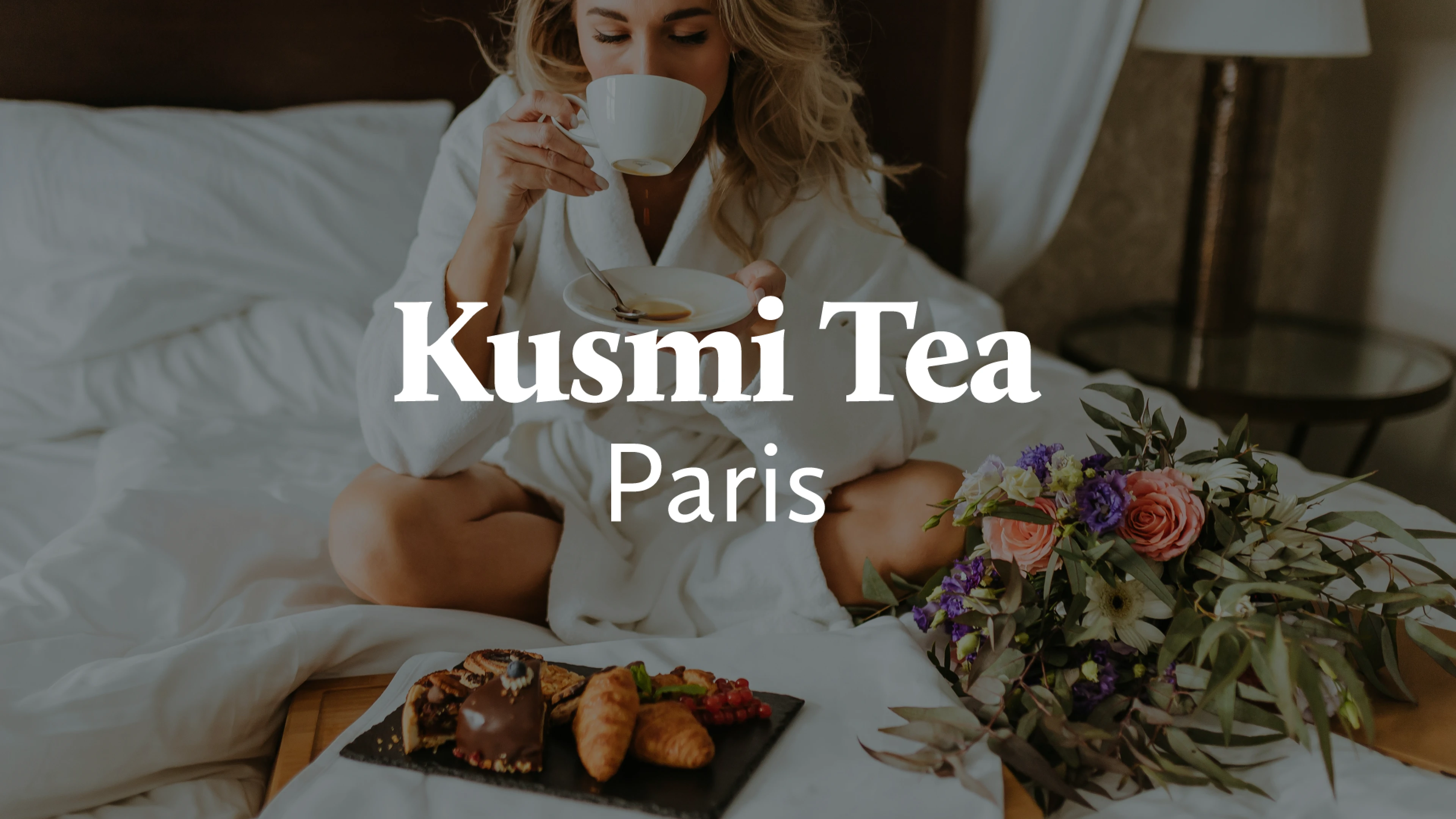 Logo Kusmi Tea et une femme qui boit du thé sur un lit avec des fleurs
