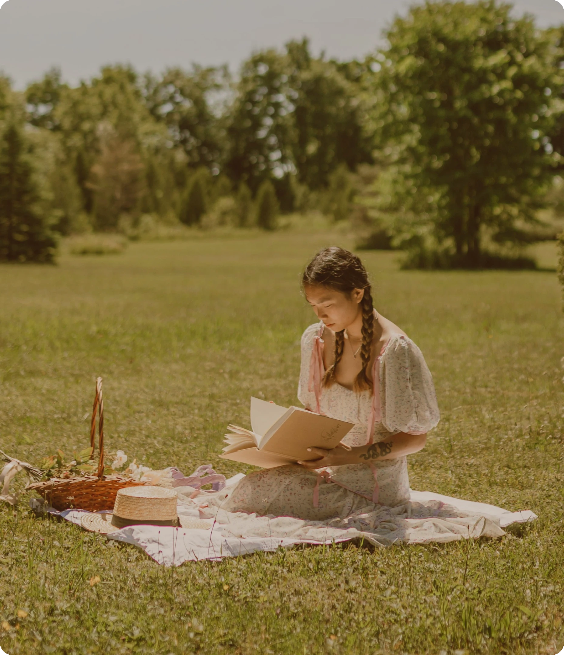 Femme dans un parc, lisant sur une couverture blanche et son panier en osier