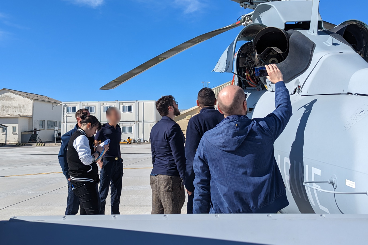 ilana prend des notes avec son équipe devant un hélico pour mettre en place les scénarios de maintenances helicopteres