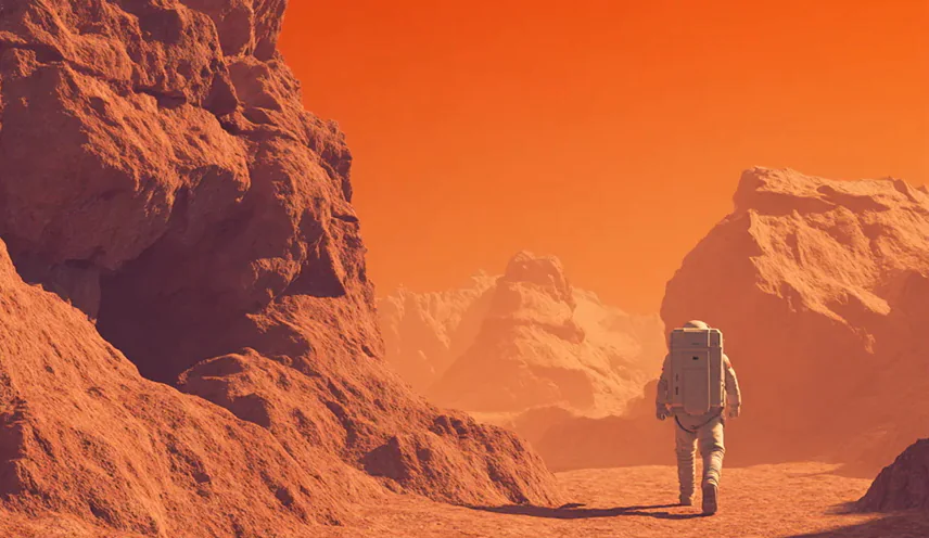 Astronaut walking through rocky canyon landscape on planetary surface.