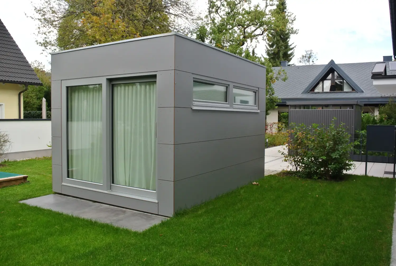 Graues, modernes Gartenbuero mit Flachdach, grosser Doppelfluegeltuer und Treppenabsatz in moderner Wohnhaussiedlung