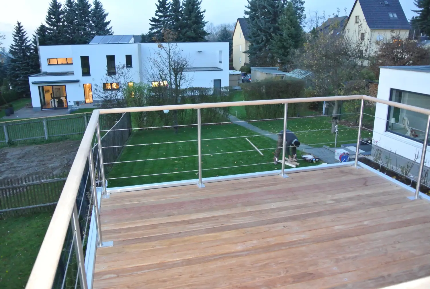 Ausblick auf Garten und Wohnhaeuser von einer Dachterrasse auf einem Gartenhaus aus, mit Holzdeck und Gelaender aus Holz und Stahl
