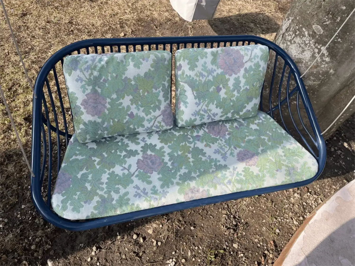 Glaenzende, dunkelbau lackierte Outdoor Schauckel mit gruen-lila gebluemten Polster der Designerin Paola Lenti